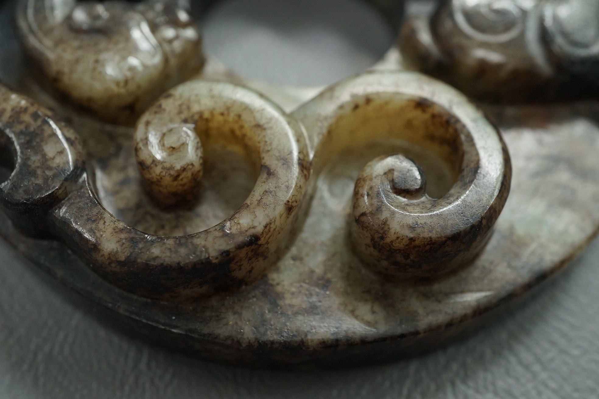 A Chinese pale celadon and black jade bi disc
